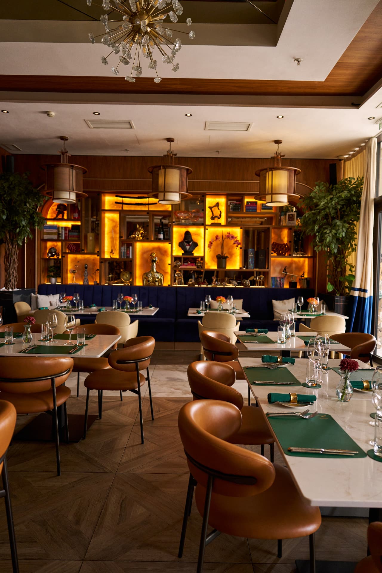 The dining room at Moments Montenegro, set for service with marble tables, leather chairs and warm gold light